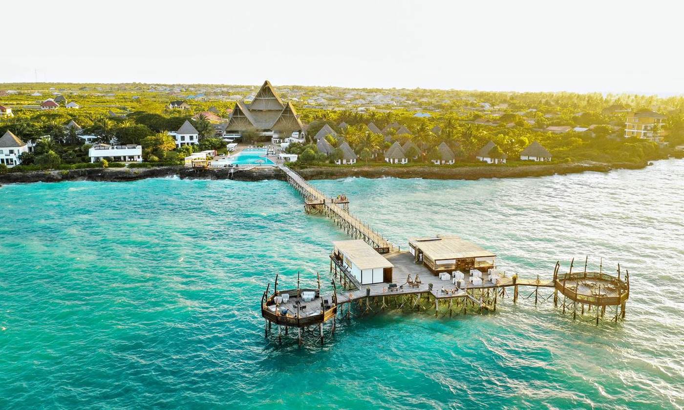 Long wooden pier over turquoise water leading from a Zanzibar beach resort